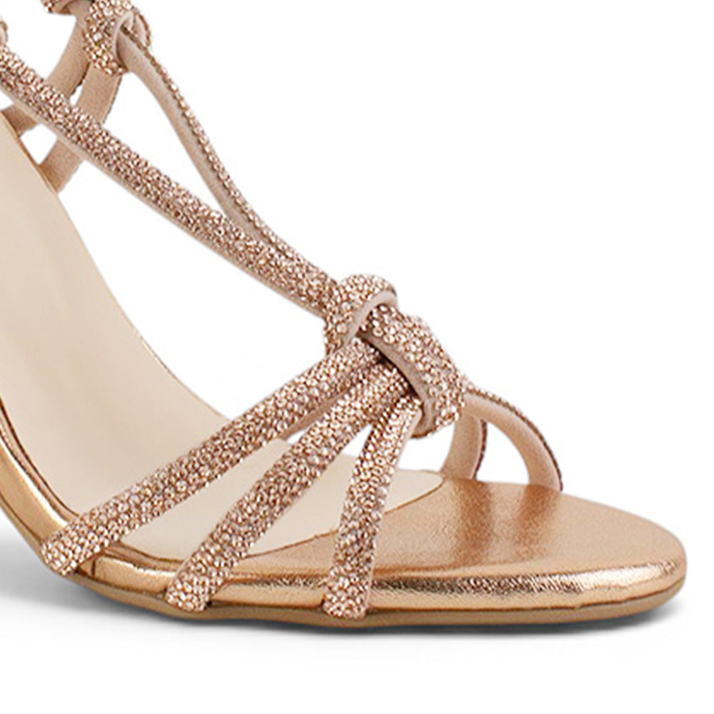 detalle del material sintético en las zapatillas oro rosado para dama con tiras cruzadas de brillos  