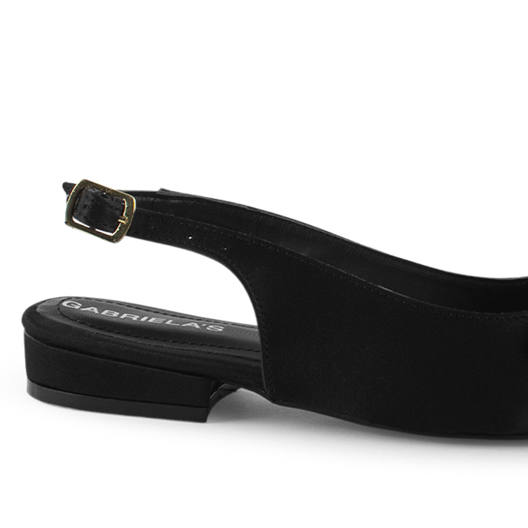 Vista trasera de flat negros para mujer con diseño destalonado de piso y pulsera con hebilla ajustable