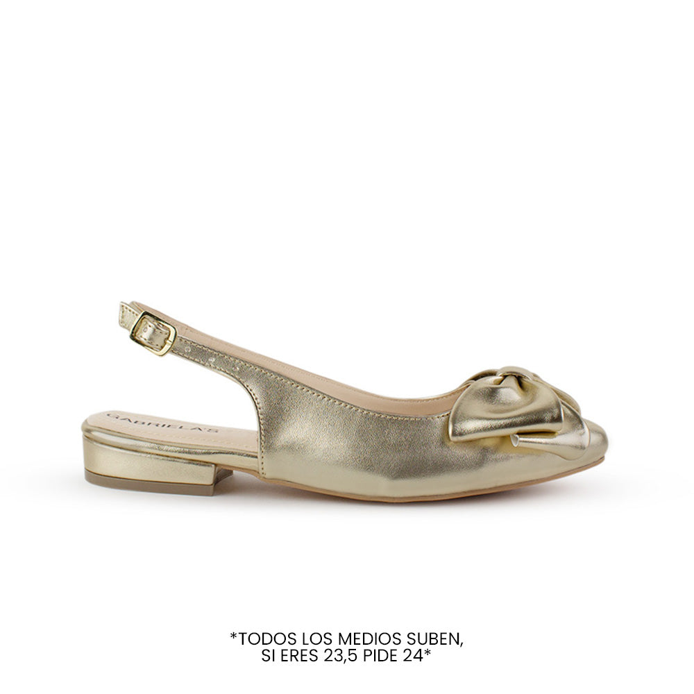Vista lateral de flats dorados para mujer con moño en punta fina, destalonado y con correa ajustable