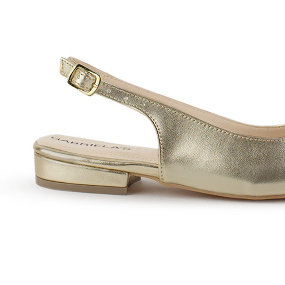 Vista trasera de flat dorados para mujer con diseño destalonado de piso y pulsera con hebilla ajustable