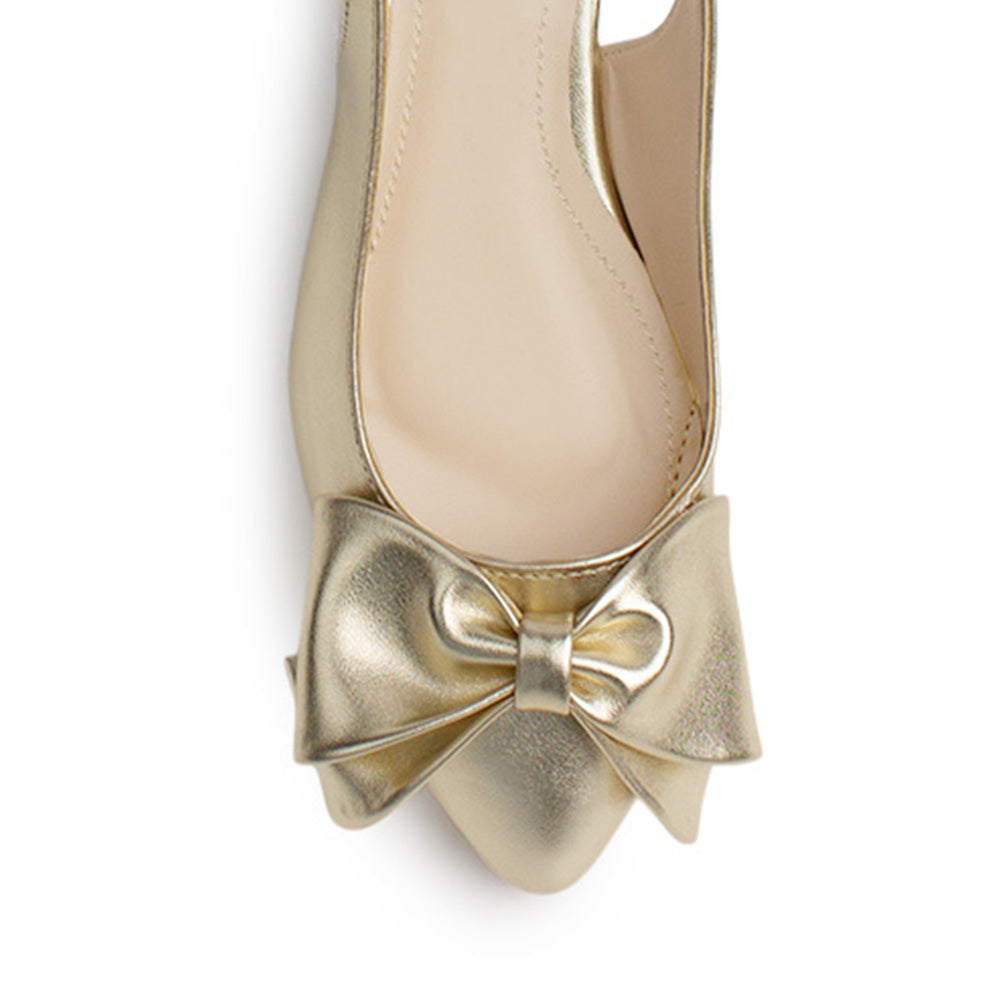 Vista de material sintético en flats dorados para mujer con moño en punta fina destalonado con pulsera ajustable trasera