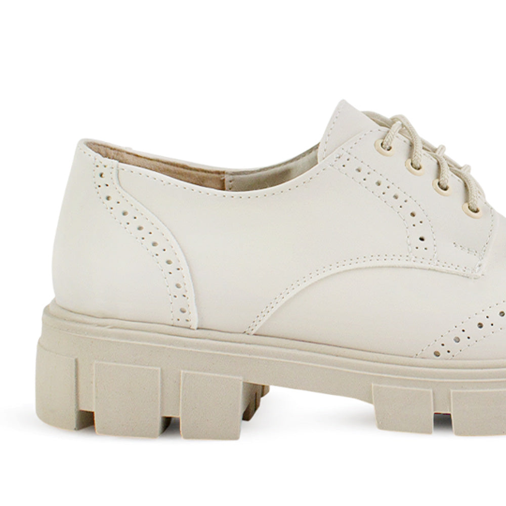 Vista trasera del tacón bajo 4cm y suela dentada tipo track del mocasín beige chunky para dama 