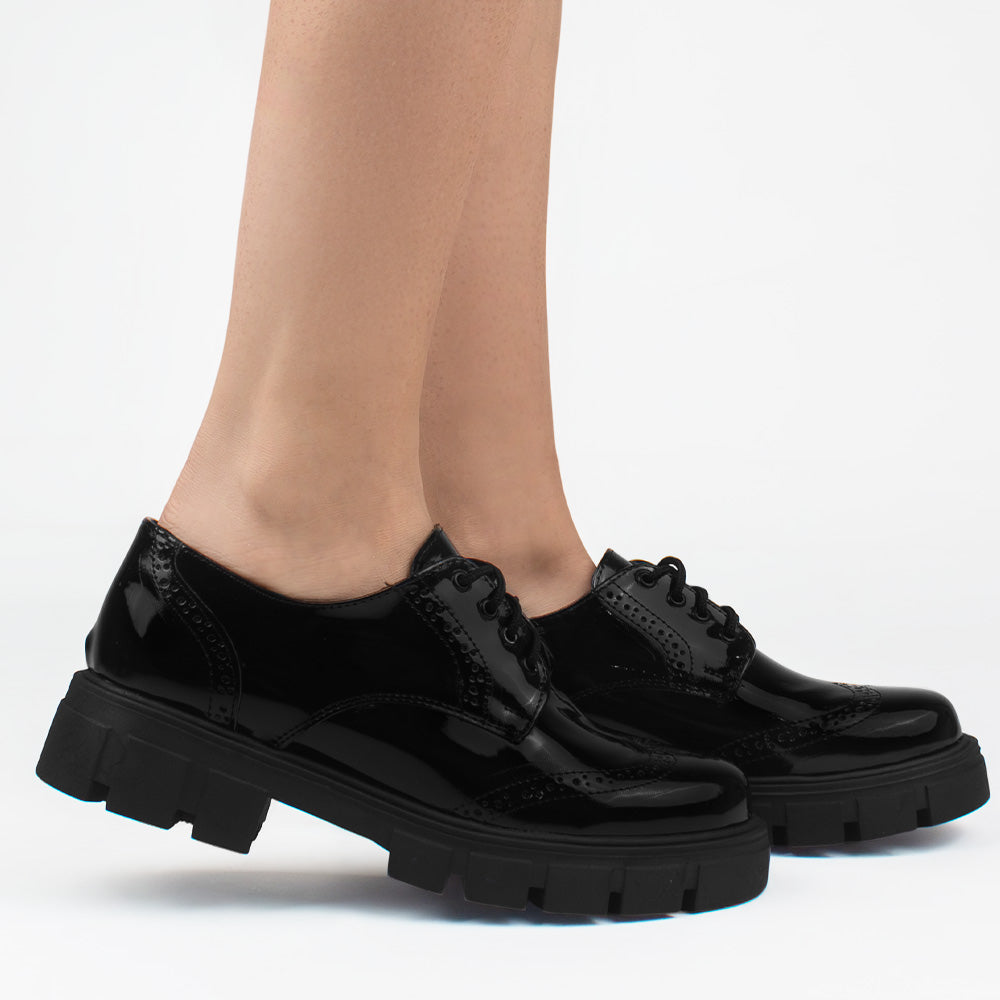 Mocasines negros chunky de charol con suela dentada tipo track, cordones para mayor ajuste y detalles clásicos 