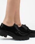 Mocasines negros chunky de charol con suela dentada tipo track, cordones para mayor ajuste y detalles clásicos 
