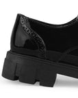 Vista trasera del tacón bajo 4cm y suela dentada tipo track del mocasín negro chunky para dama 