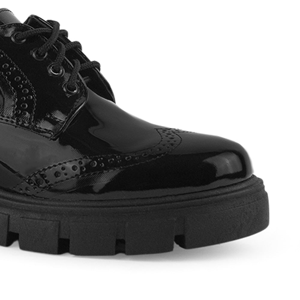 Detalle del material charol en el mocasín negro para dama con cordones funcionales y suela dentada tipo track 