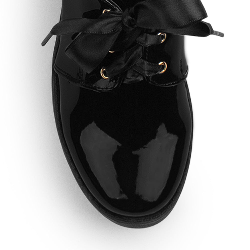 Vista del detalle en listones del mocasín negro tipo chunky de punta redonda con plataforma y tacón grueso tamaño bajo 5cm