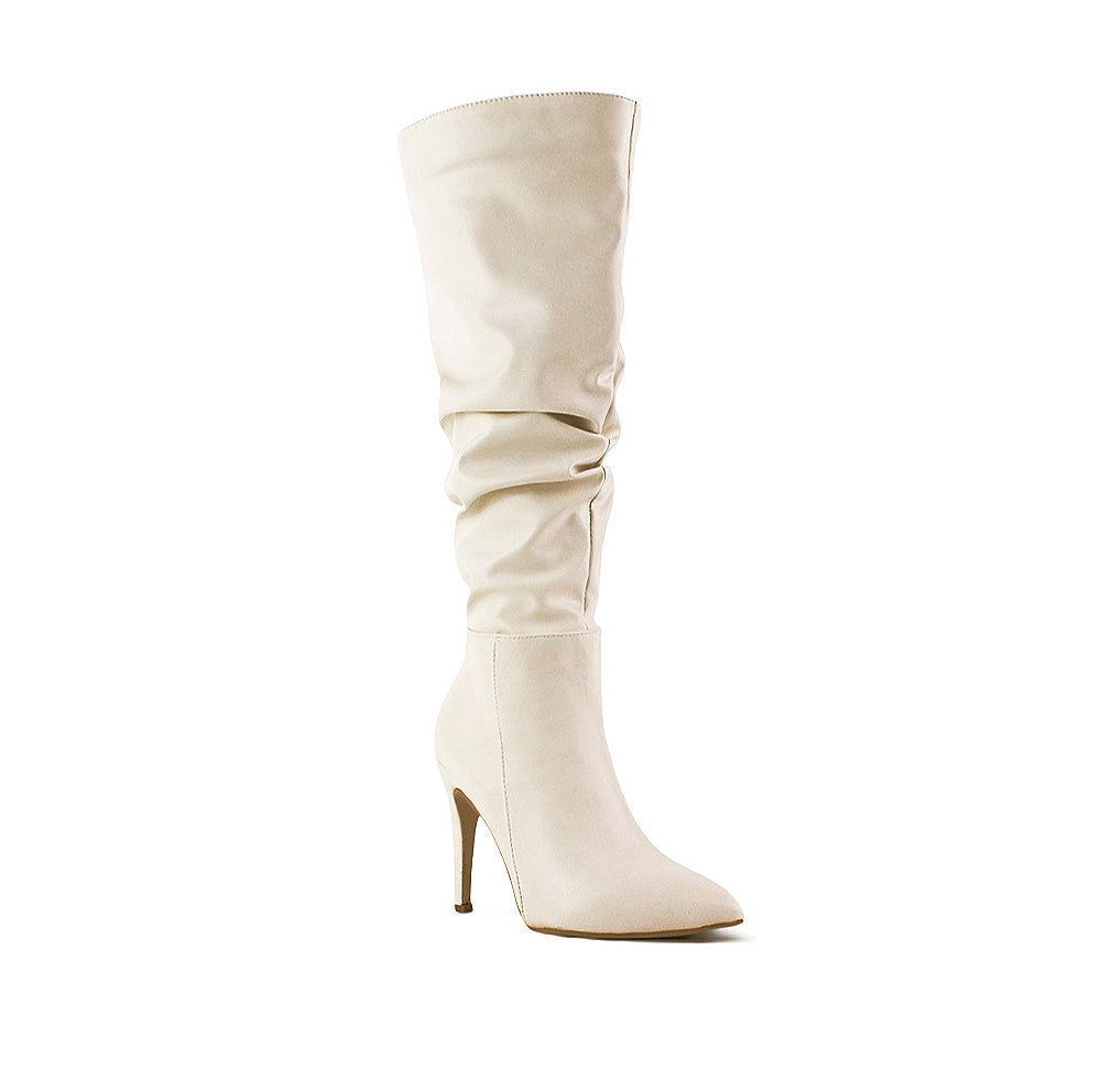 vista diagonal de botas beige con terminación en punta, tacón alto y delgado 11 cm para dama
