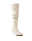 vista diagonal de botas beige con terminación en punta, tacón alto y delgado 11 cm para dama