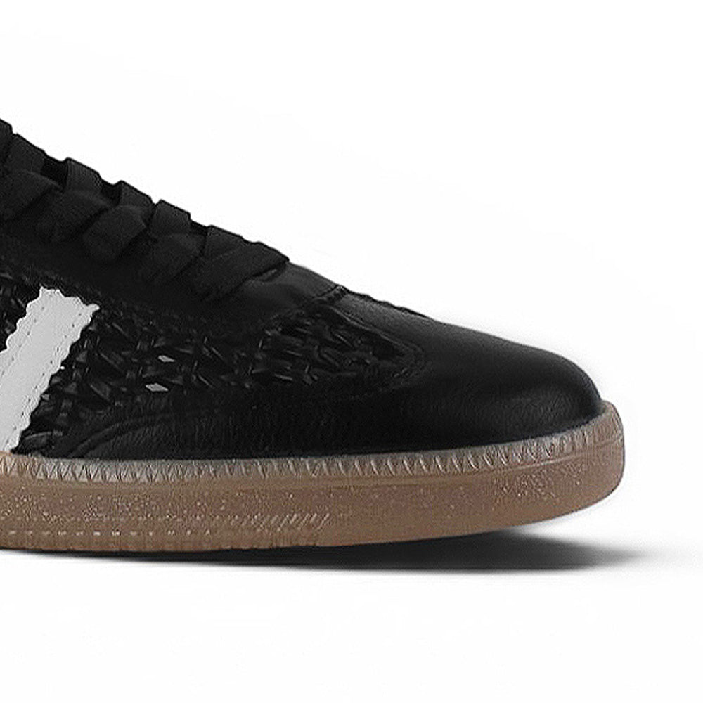 Detalle del material sintético en tenis negro con blanco para dama de piso y detalles tejidos 