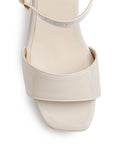 Vista de material charol en zapatilla de diseño descubierto para mujer con pulsera ajustable y tacón medio de 8cm en color beige 
