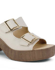 Vista a detalle de doble correa con hebillas ajustables en zapatilla beige para mujer con plataforma al frente y tacón grueso de 8cm