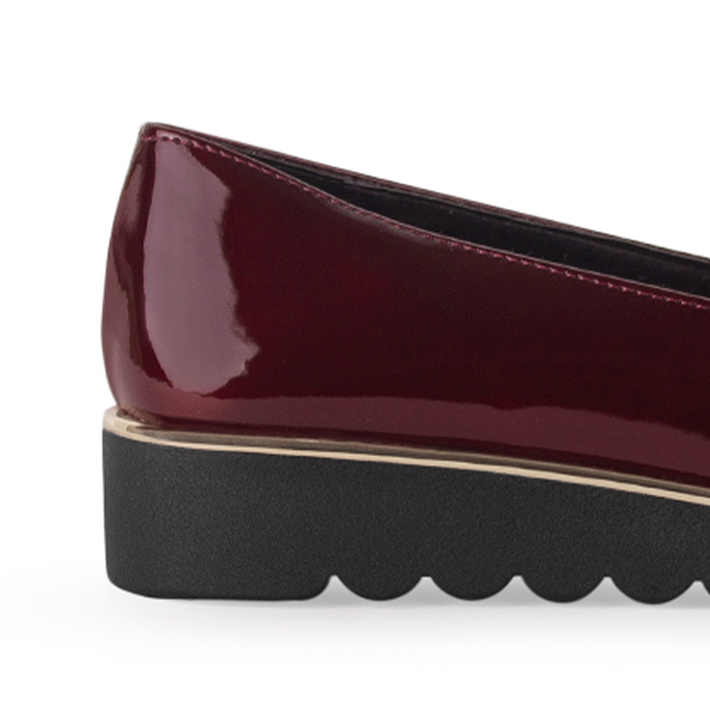 Vista del detalle metálico en la plataforma baja 3cm del mocasín vino para dama con herraje decorativo