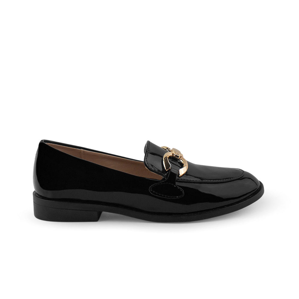 Vista lateral del mocasín negro de charol con suela de piso, herraje metálico decorativo para dama  