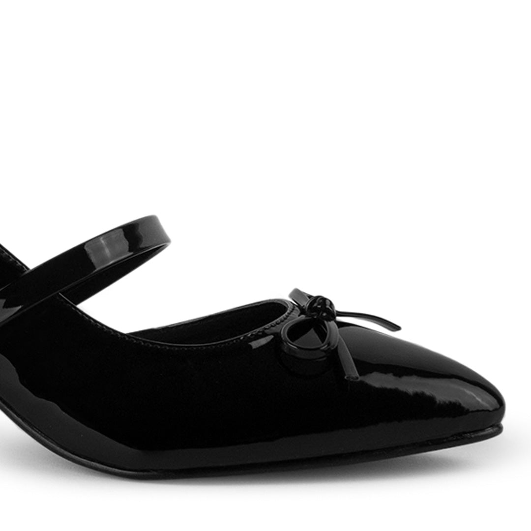 Vista a detalle de moño en punta fina cerrada de zapatilla negra destalonada para mujer con tacón bajo de 6cm 