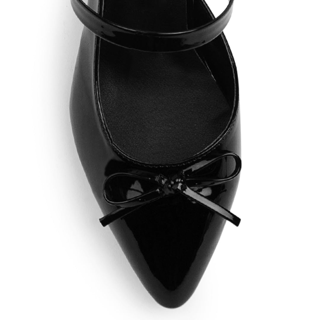 Vista de material charol en zapatilla negra para mujer con moño destalonada y tacón ancho bajo de 6cm