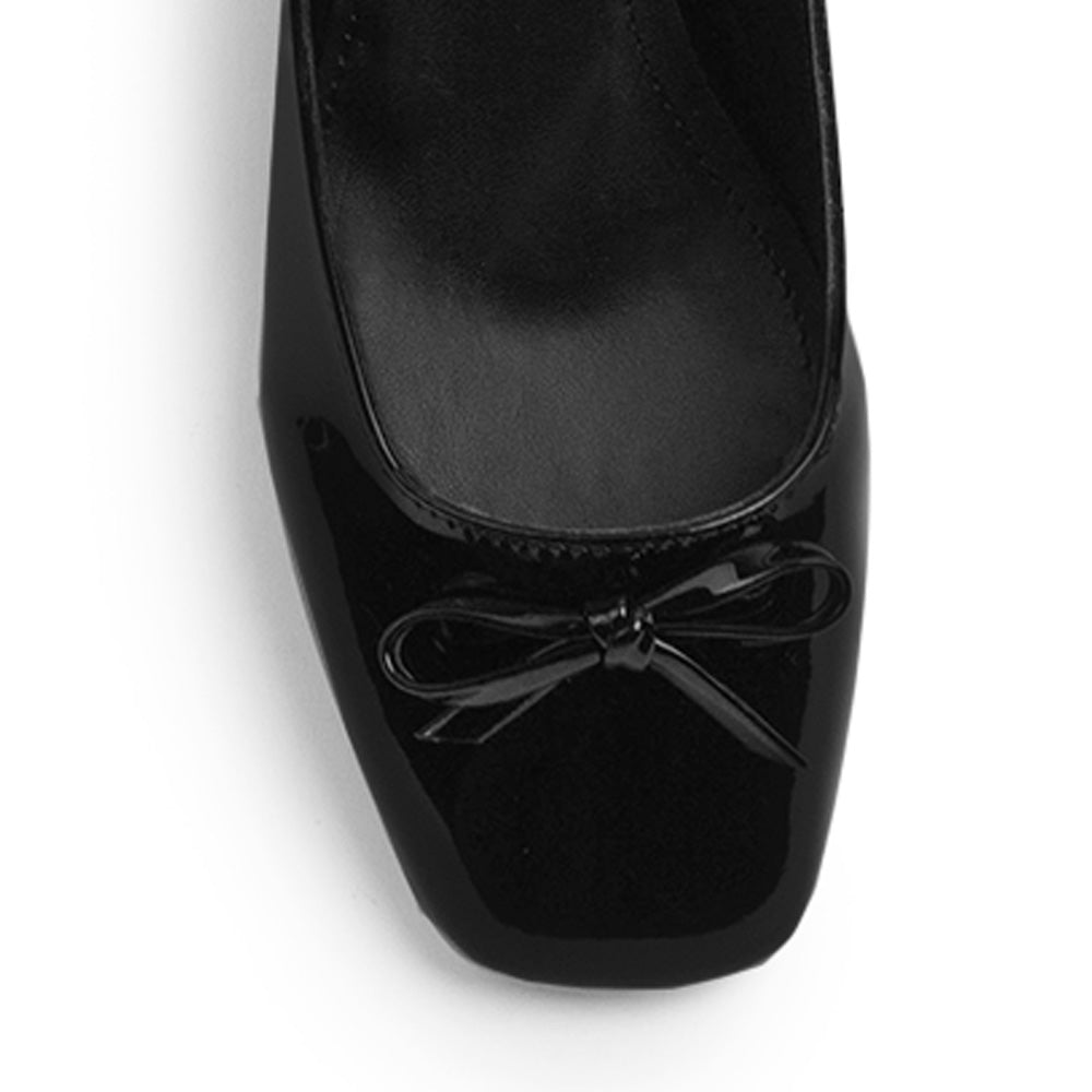 Vista de material charol en zapatilla negra destalonada para mujer con moño en punta cerrada y tacón bajo de 5cm