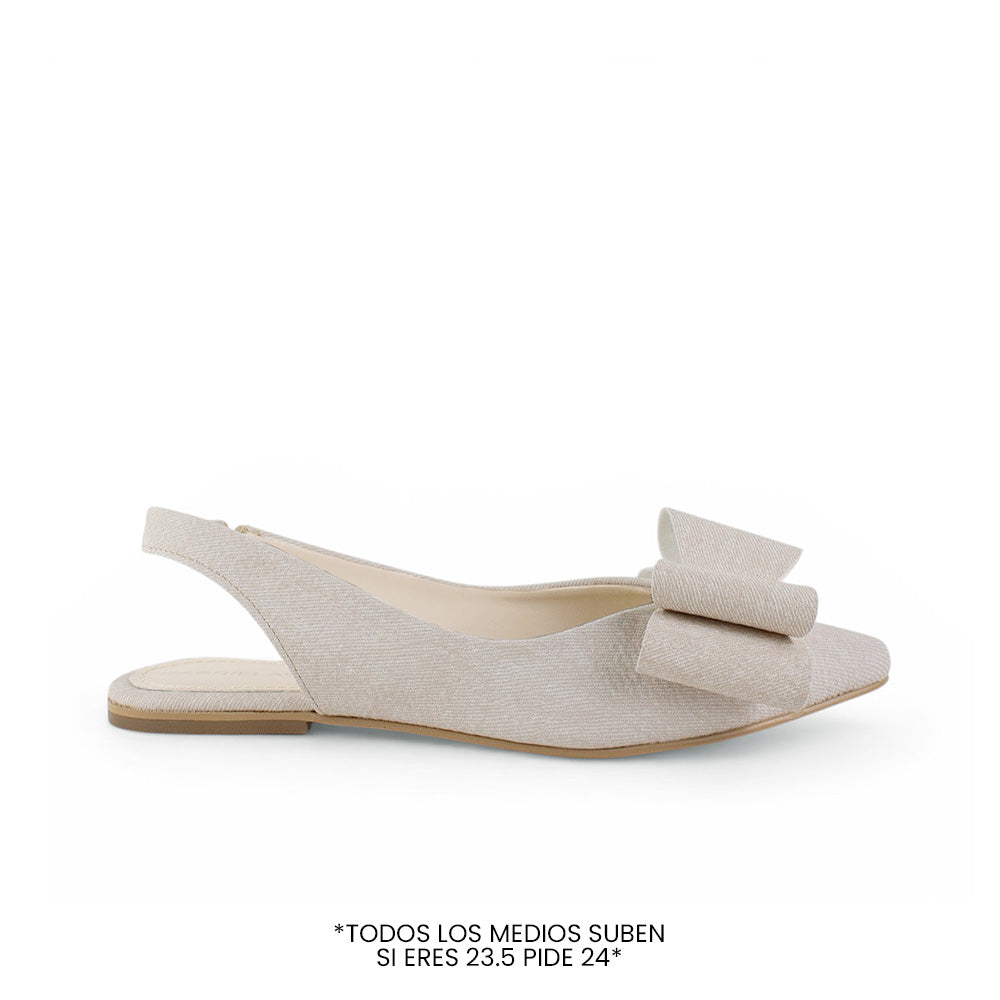 Vista lateral de flat beige para mujer con moño grande en punta fina cerrada  y correa elástica trasera de piso