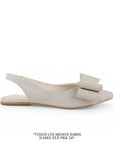 Vista lateral de flat beige para mujer con moño grande en punta fina cerrada  y correa elástica trasera de piso