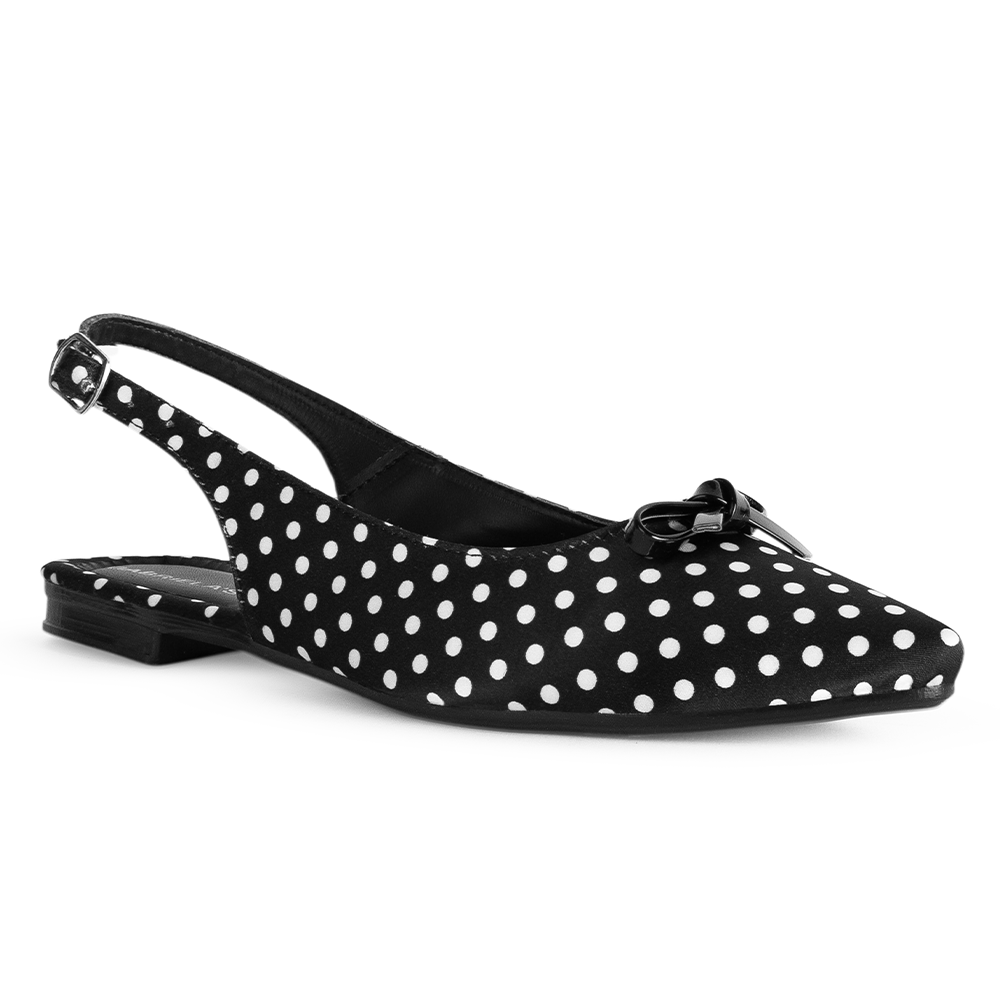 Vista diagonal de flats negro con lunares blancos, suela de piso, pulsera ajustable y moño decorativo