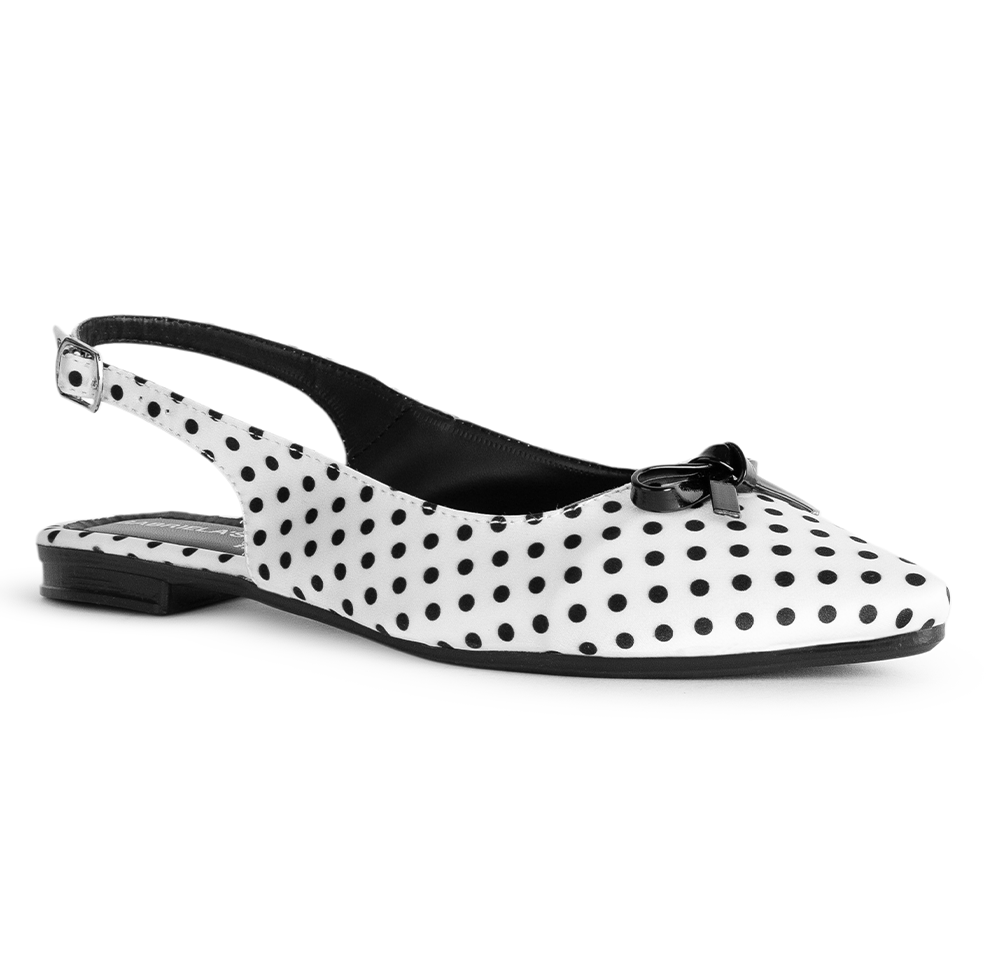 Vista diagonal de flats blanco con lunares negros, suela de piso, pulsera ajustable y moño decorativo