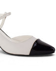 Vista a detalle de punta fina cerrada en zapatilla beige con negro de diseño destalonado con correa y tacón de 7cm