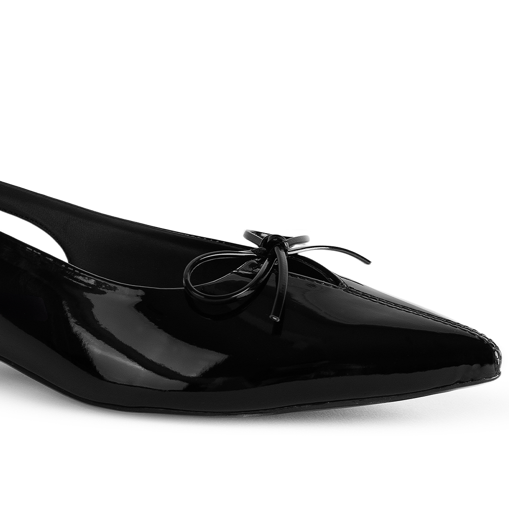 Detalle del material charol en la zapatilla negra para dama con moño decorativo y punta fina 