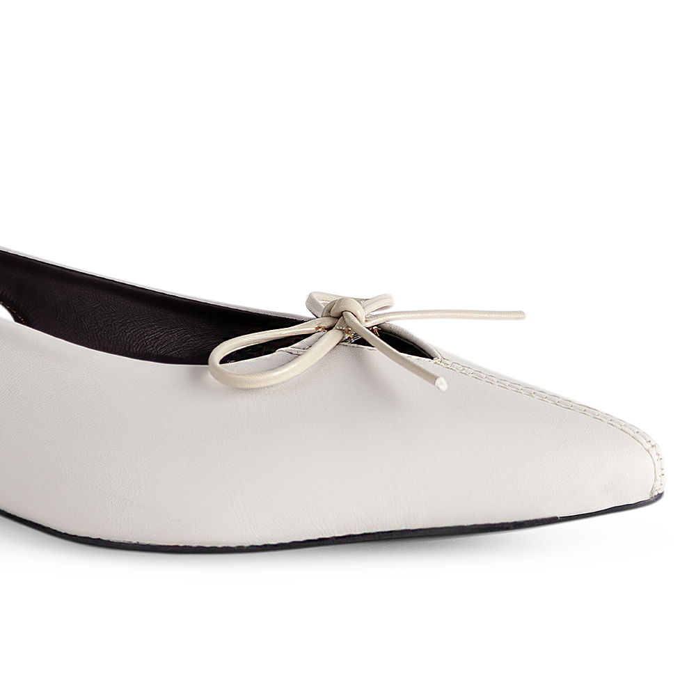 Detalle del material sintético en la zapatilla beige para dama con moño decorativo y punta fina 