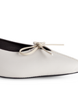 Detalle del material sintético en la zapatilla beige para dama con moño decorativo y punta fina 
