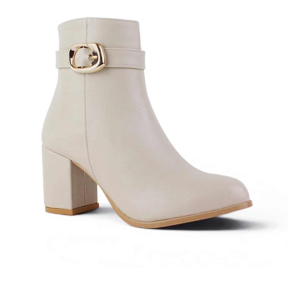 vista diagonal de botas beige para dama con detalle en hebilla oro y tacón 