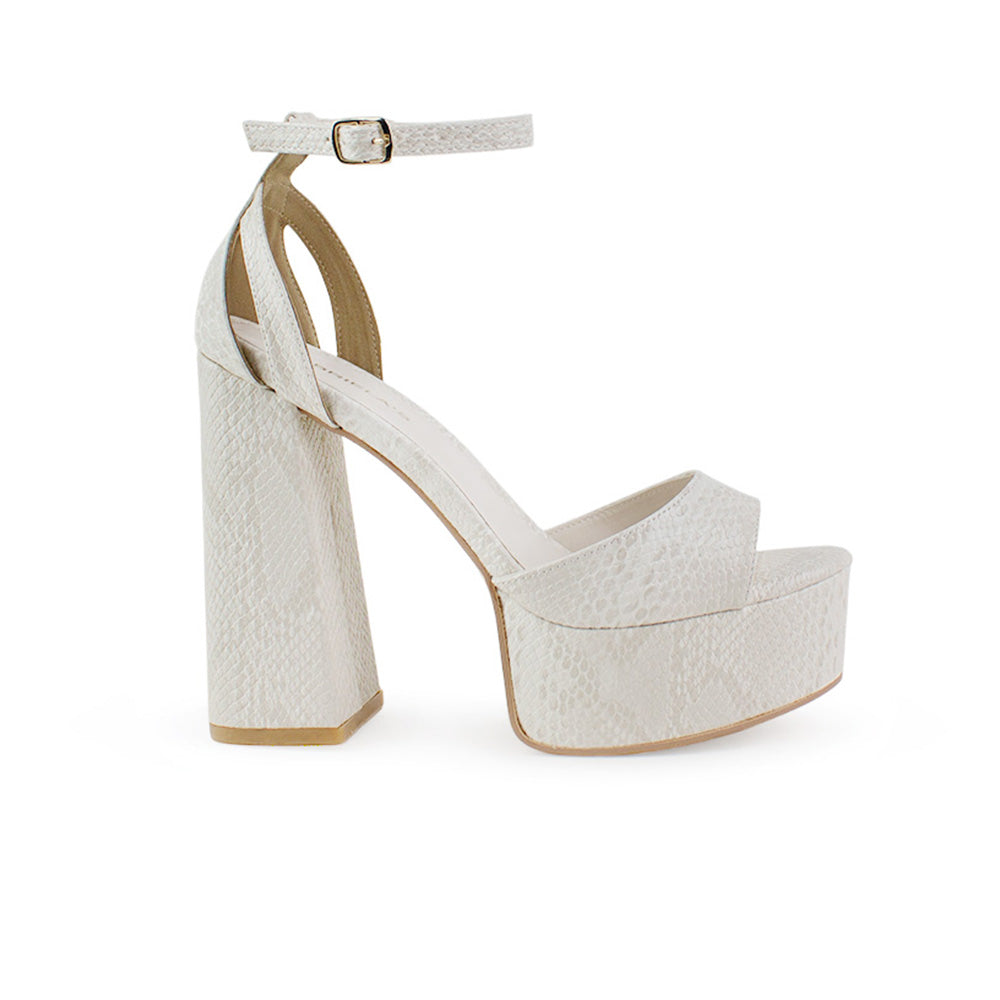 Vista lateral de zapatilla beige en acabado grabado para mujer con pulsera y tacón alto 13cm