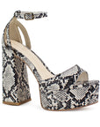 Vista diagonal de zapatilla para mujer con pulsera y tacón alto 13cm en color beige con negro