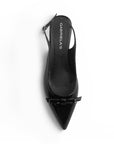 vista superior de zapatillas negras de charol para dama con talón descubierto y terminación en punta