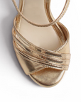 vista del detalle frontal de las zapatillas oro con pulsera y plataforma de dama