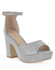 Vista diagonal de zapatilla para mujer con pulsera y tacón ancho en color plata brilloso 