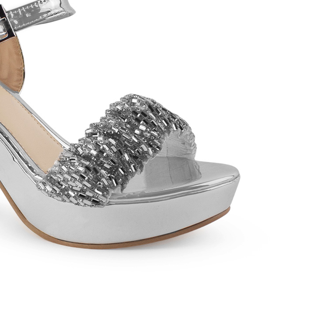 Vista a detalle de tira ancha brillosa en zapatilla plata para mujer con pulsera y tacón ancho 10cm