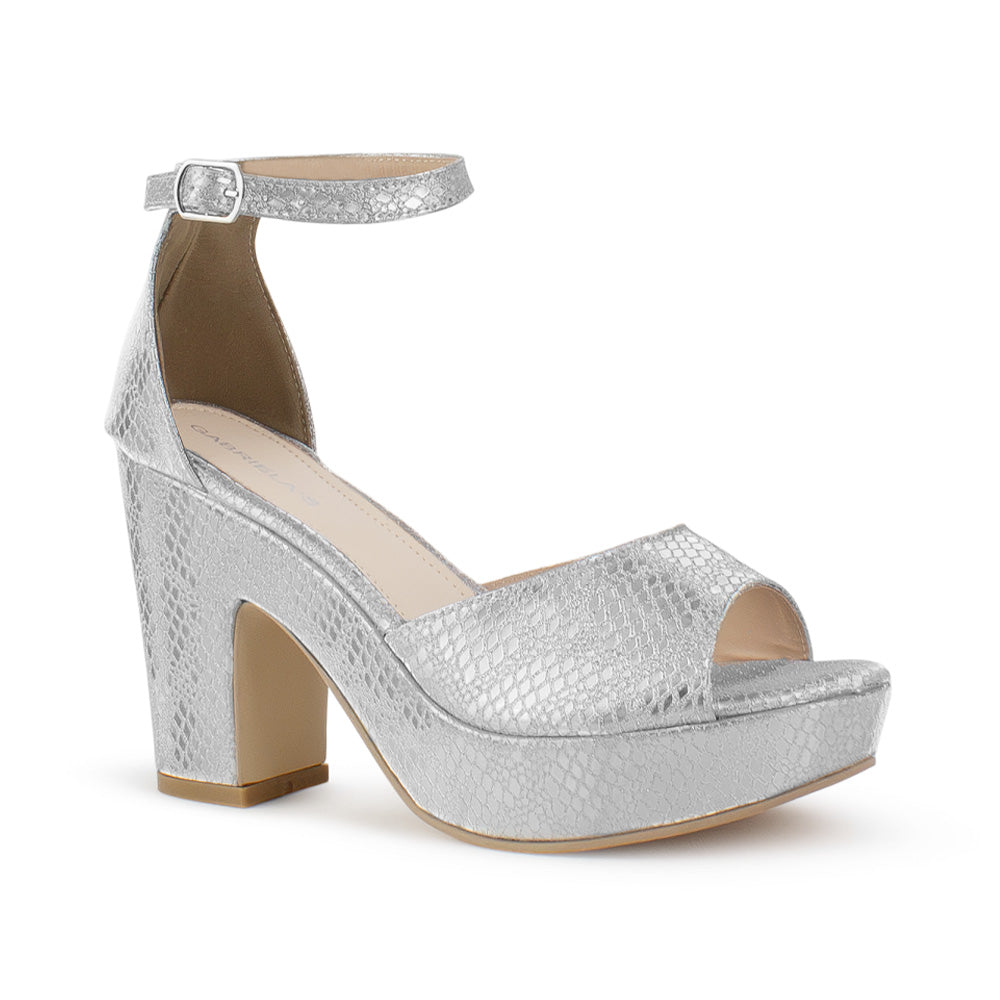 Vista diagonal de zapatilla para mujer con pulsera y tacón ancho en color plata